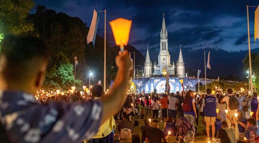 Lourdes candles at night arm pilgrimage tour